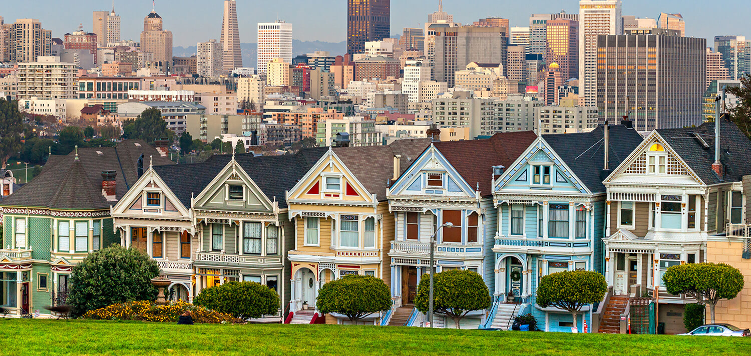 The Painted Ladies, colorful Victorian homes along the eastern side of Alamo Square Park in San Francisco with the city skyline in the background.