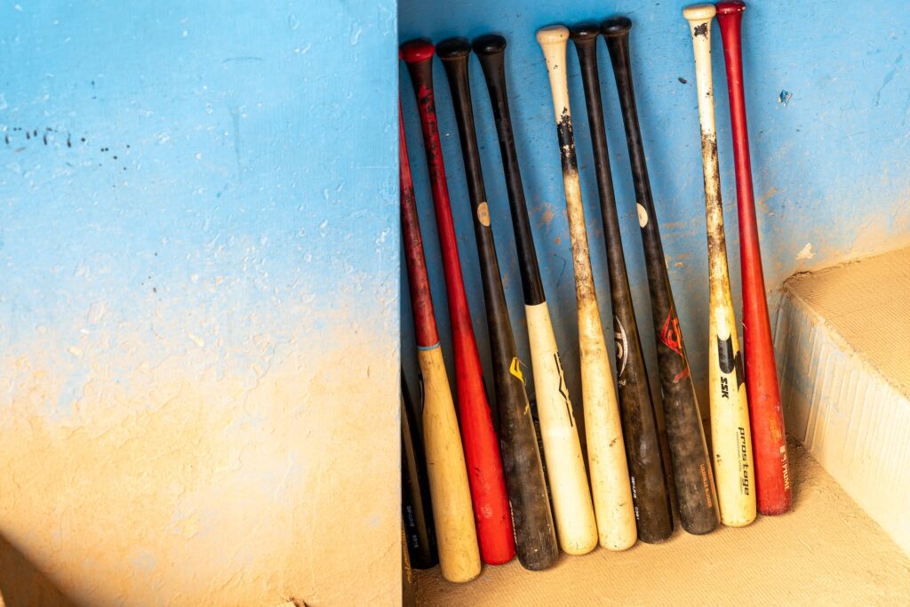 A row of baseball bats standing up against the wall of a dugout.