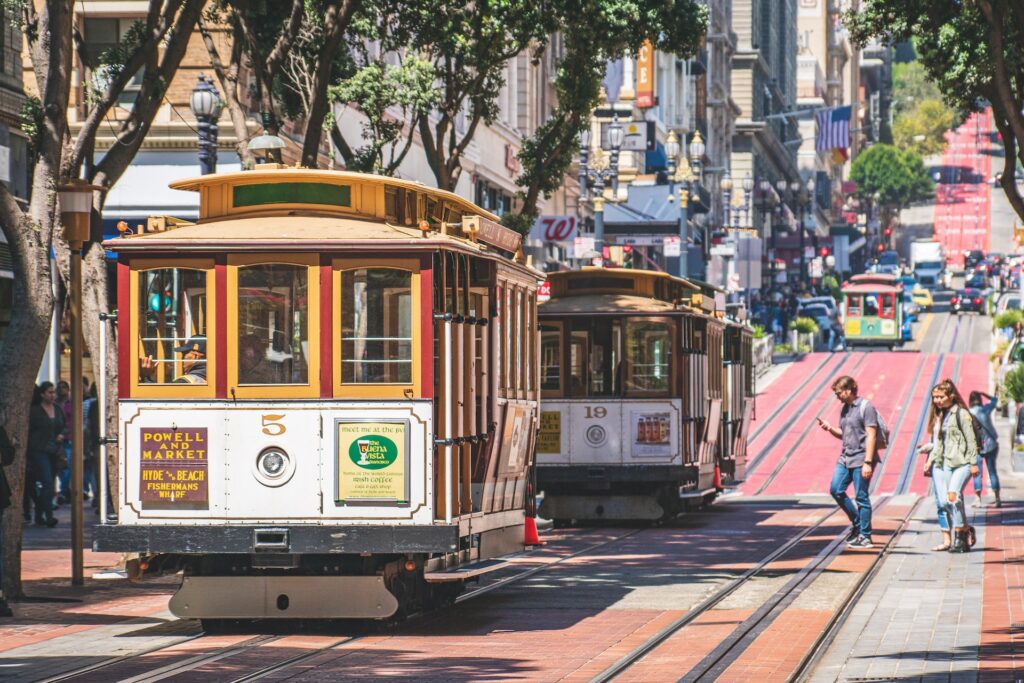 Several street cars traveling down the streets of San Francisco.