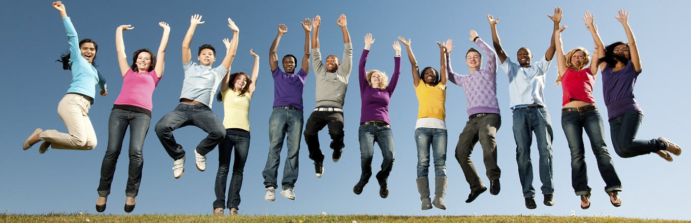 A diverse group of young adults in a line smiling and jumping in the air.
