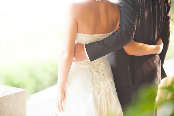 Bride and groom with their hands around each other's waists.